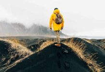 한국 여행객, 이제 ‘날씨’ 보고 떠난다 악천후가 드리운 해안 풍경 앞에 서 있는 여행자의 뒷모습