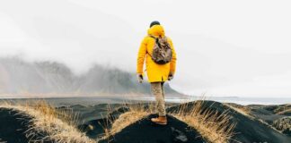 한국 여행객, 이제 ‘날씨’ 보고 떠난다 악천후가 드리운 해안 풍경 앞에 서 있는 여행자의 뒷모습