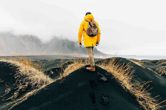 악천후가 드리운 해안 풍경 앞에 서 있는 여행자의 뒷모습