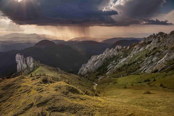 먹구름과 비구름이 드리운 산악 지형의 풍경