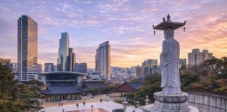 Bongeunsa Temple courtyard and standing Buddha statue with the Gangnam skyline at sunset in Seoul