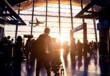공항 터미널에서 석양을 배경으로 비행기를 바라보는 여행객들