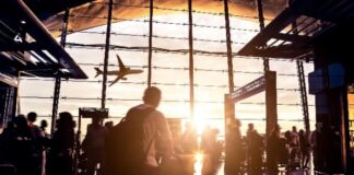 공항 터미널에서 석양을 배경으로 비행기를 바라보는 여행객들