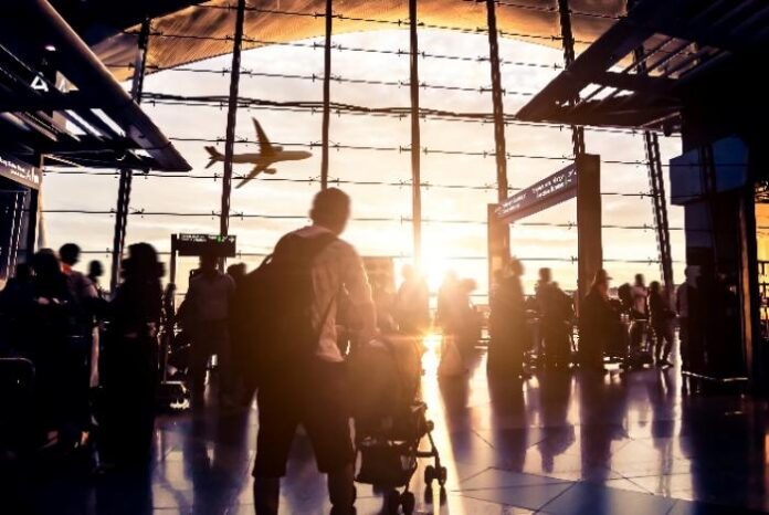 공항 터미널에서 석양을 배경으로 비행기를 바라보는 여행객들