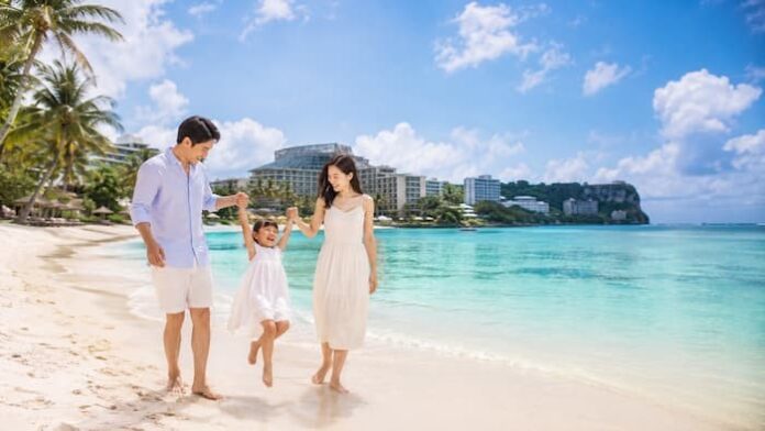 괌 해변을 배경으로 가족 여행객이 휴양을 즐기는 장면