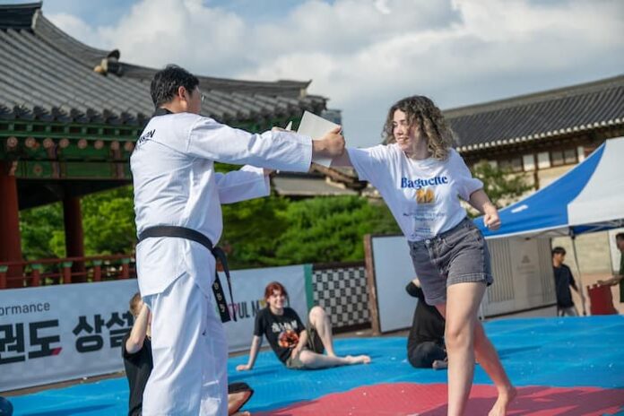 seoul-taekwondo-performance-namsangol-foreign-tourist-2026 서울시 태권도공연에서 외국인 관광객이 태권도 체험을 하는 모습