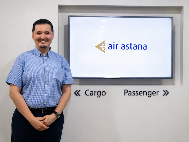 Adel Dauletbek standing by Air Astana office sign