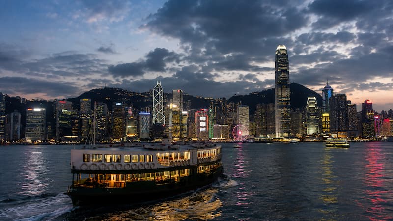 A ferry crossing Victoria Harbour with the Hong Kong skyline at dusk