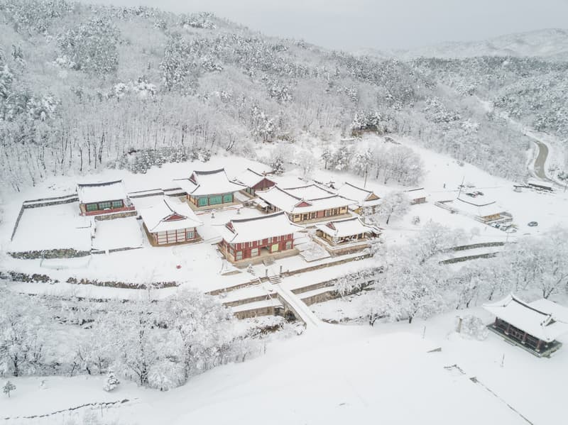 눈 덮인 금강산 자락과 건봉사 전각을 내려다본 겨울 항공 전경