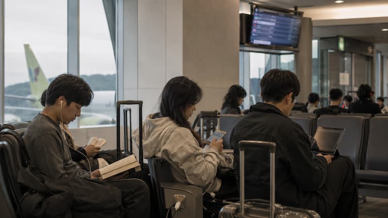 공항에서 항공편 지연 상황을 알리고 일정을 조정하는 여행객