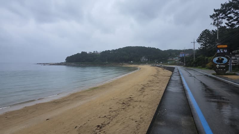 비 내린 해안도로와 젖은 백사장이 이어지는 고성 초도해수욕장