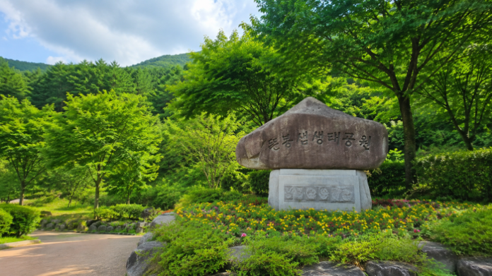 울창한 여름 숲에 자리한 장수 뜬봉샘생태공원 표지석