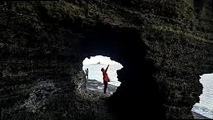 제주 용머리해안 해식동굴의 둥근 구멍 사이로 보이는 바다와 탐방객