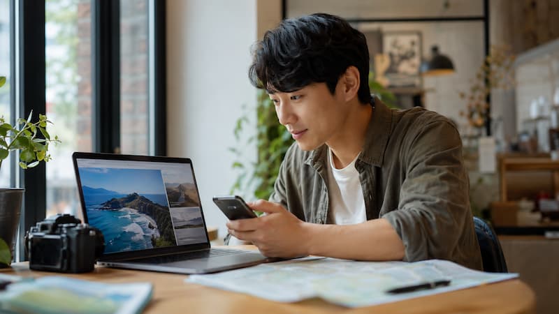 A Korean independent traveler researching destination information on a laptop and smartphone