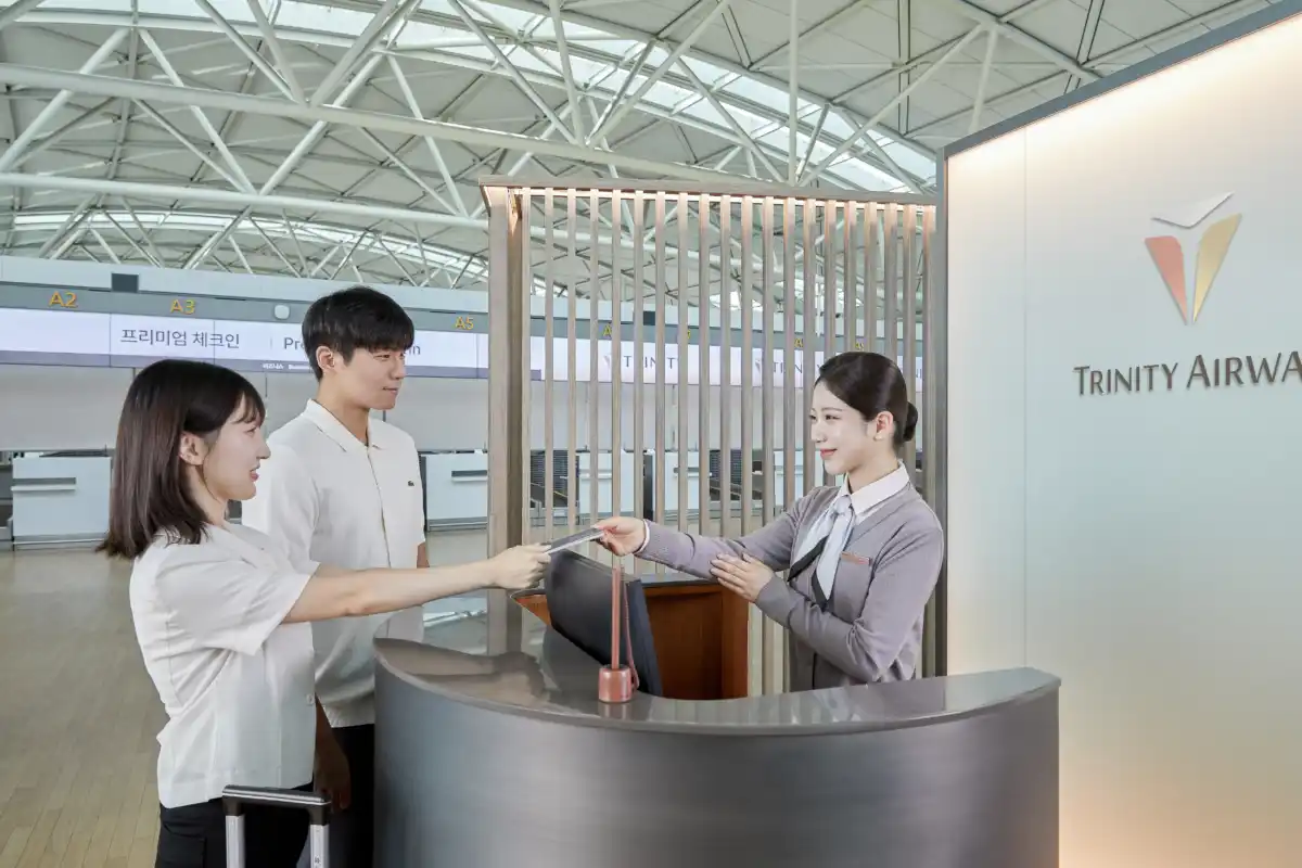 트리니티항공 신규 유니폼을 착용한 직원이 인천국제공항 카운터에서 승객에게 서류를 건네는 모습