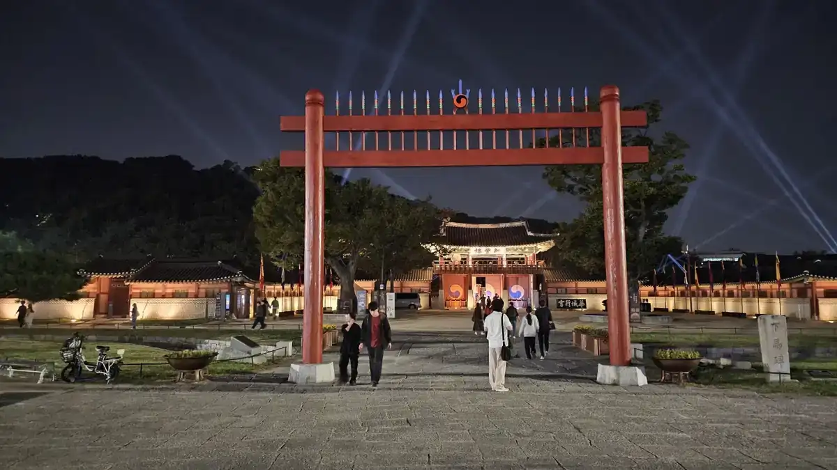 야간 조명과 빛줄기 아래 관람객들이 들어가는 화성행궁 신풍루
